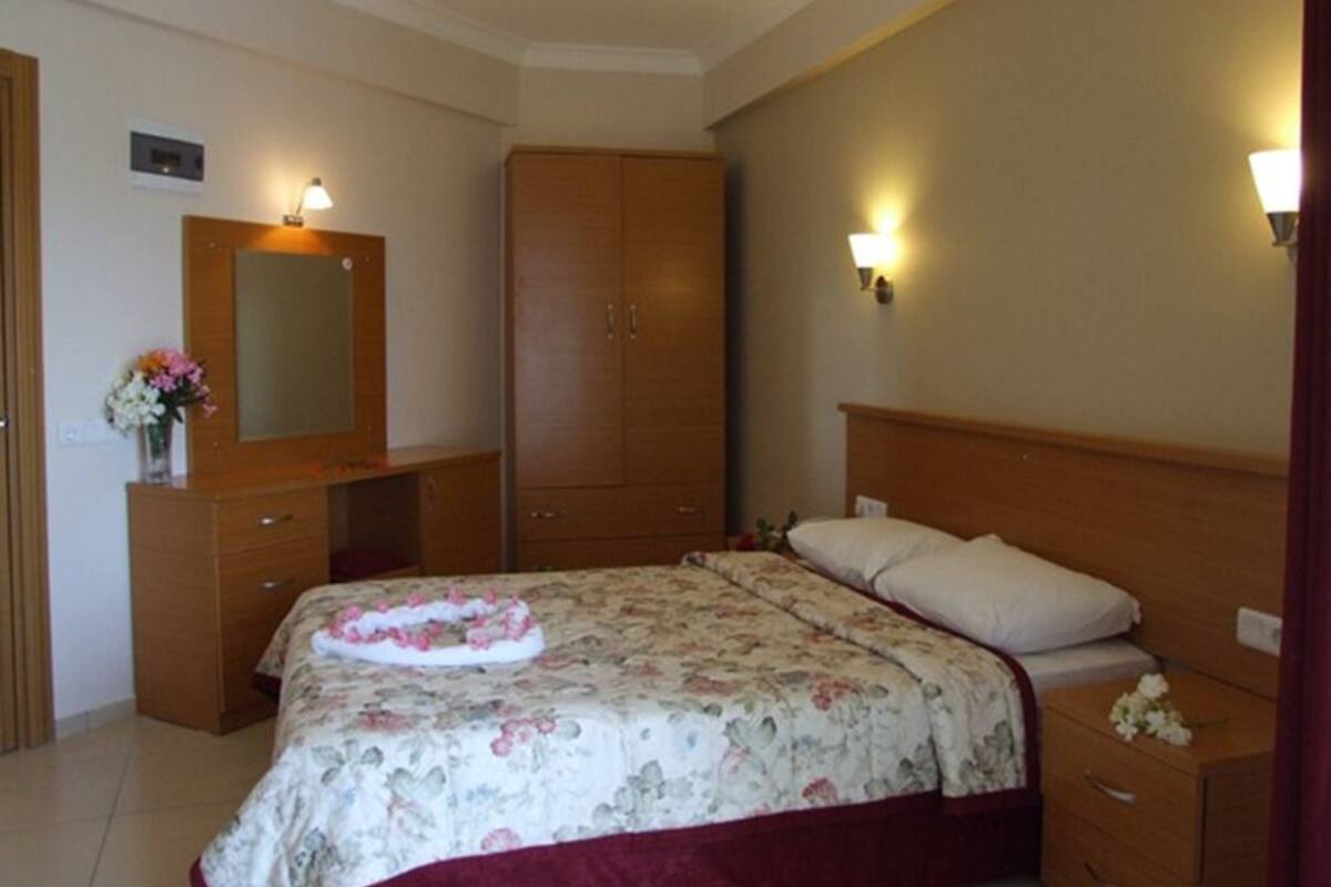 A bedroom with a bed, a wooden wardrobe, a dresser, and a nightstand.