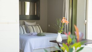 Un dormitorio con una cama, almohadas, un jarrón con flores y una mesa.