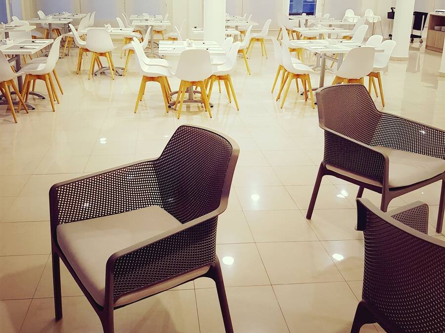 Un amplio espacio interior con varias mesas y sillas dispuestas para comer o reuniones.