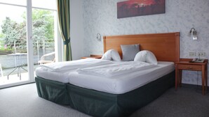 A hotel room with a large bed, a wooden headboard, a nightstand, a telephone, and a painting on the wall. - Hotel Tannerhof (Schenna)