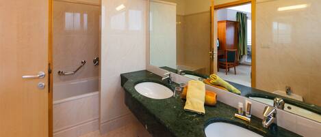 Un baño con dos lavamanos, ducha y un espejo grande.