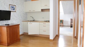 A compact kitchen with white cabinets, a wooden countertop, and a built-in TV. - Hotel Tannerhof (Schenna)