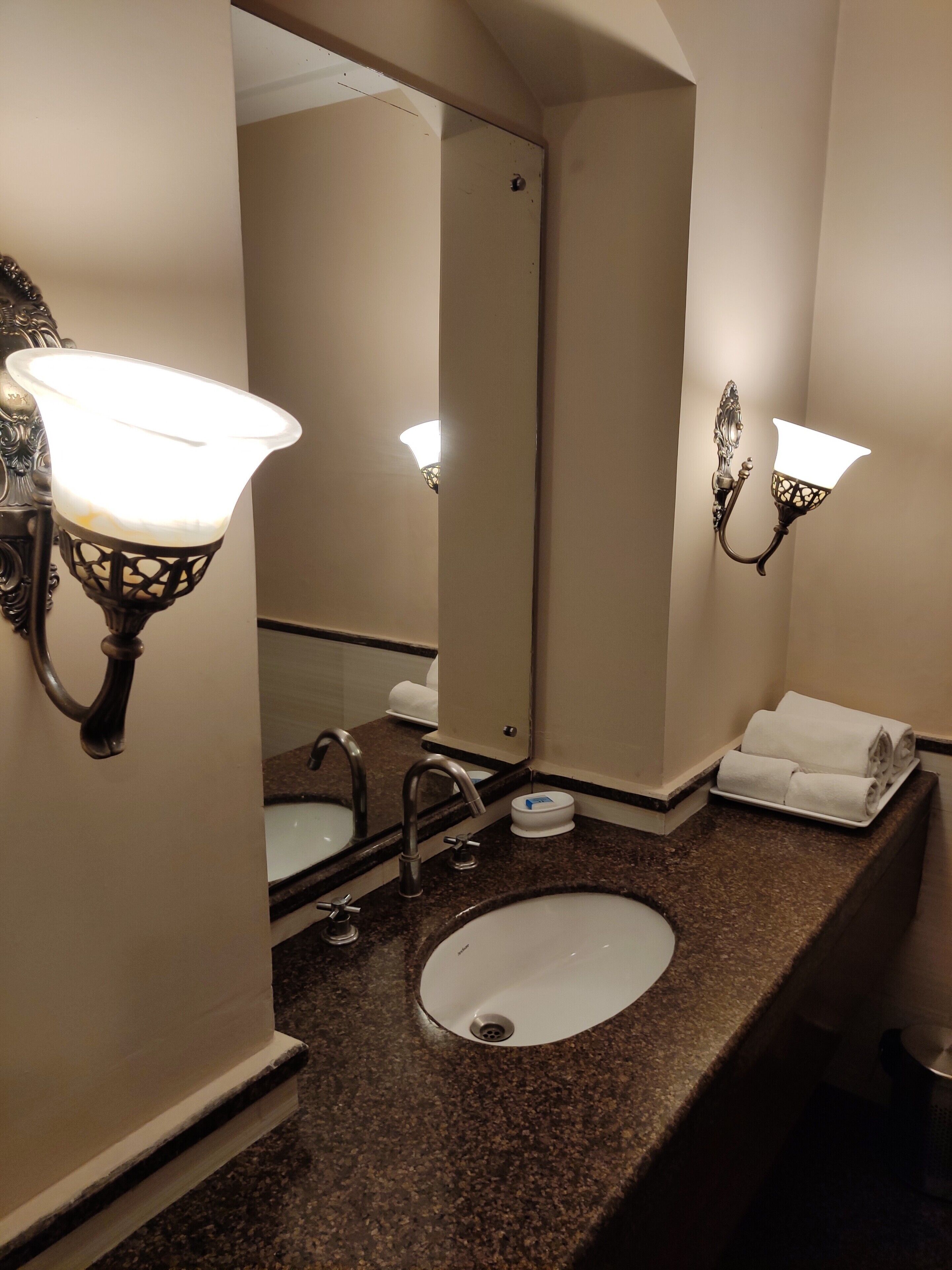 A bathroom with a sink, mirror, and two wall-mounted lights.