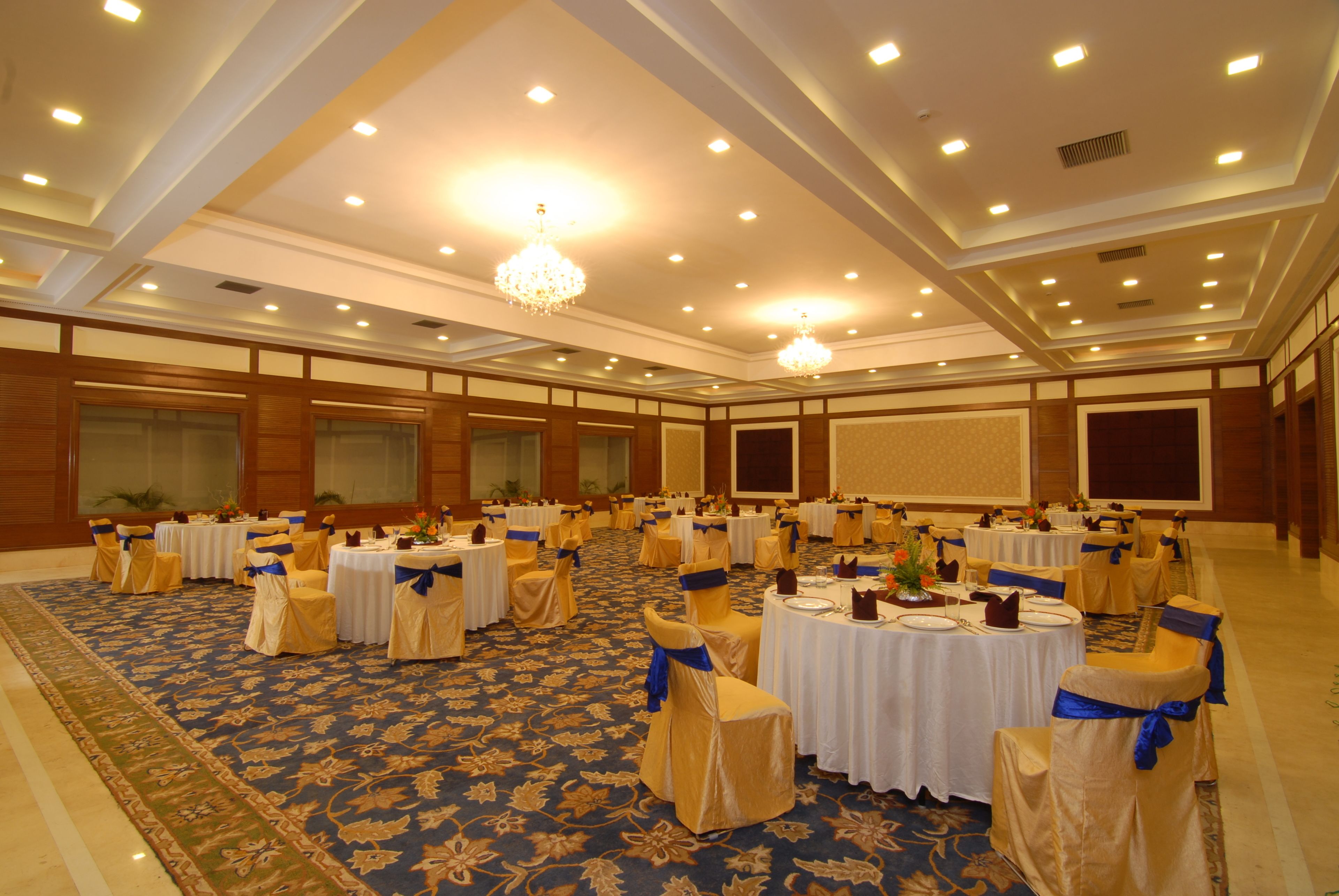 A banquet hall with round tables, chairs, and a carpeted floor.