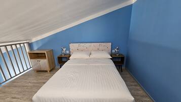 A bedroom with a bed, two bedside tables, a nightstand, a wardrobe, and a balcony with a railing.