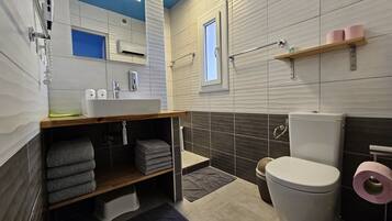 Un baño moderno con lavamanos, inodoro y zona de ducha.
