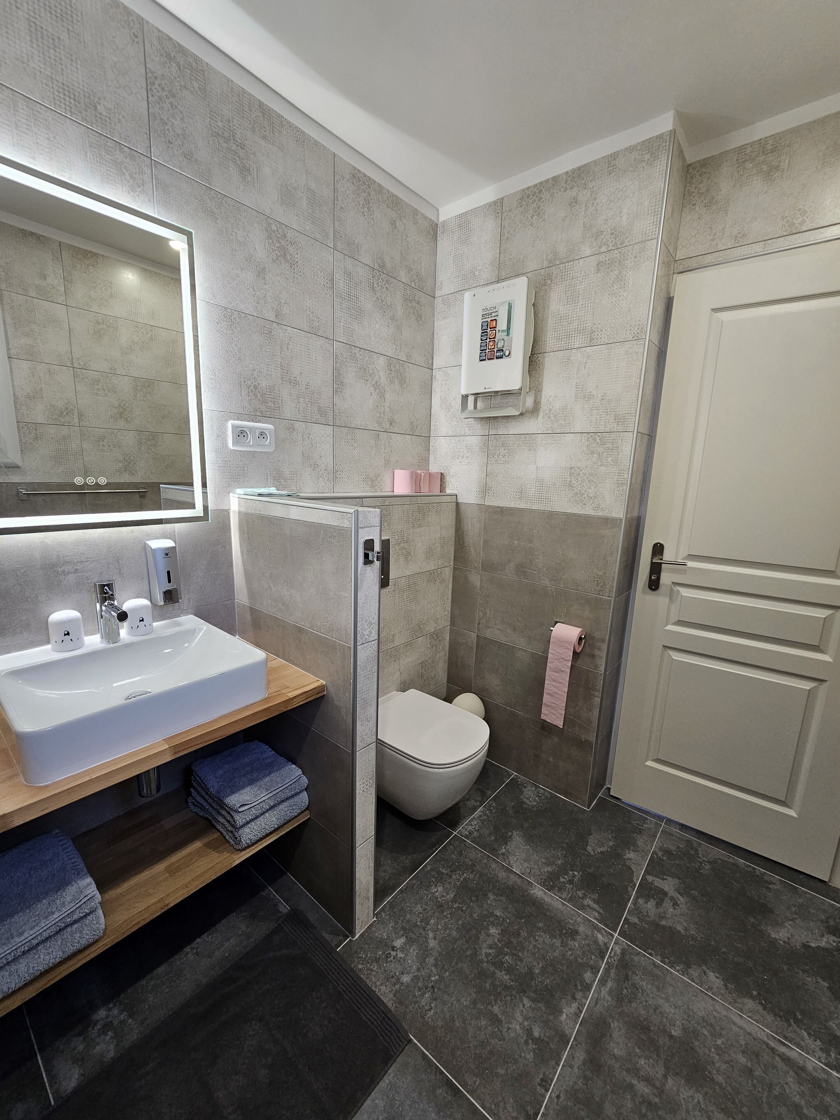 Un baño moderno con un espejo grande, un lavabo, un inodoro y una zona de ducha.
