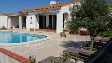 Relax by the pool surrounded by lush greenery and a seating area with lounge chairs.