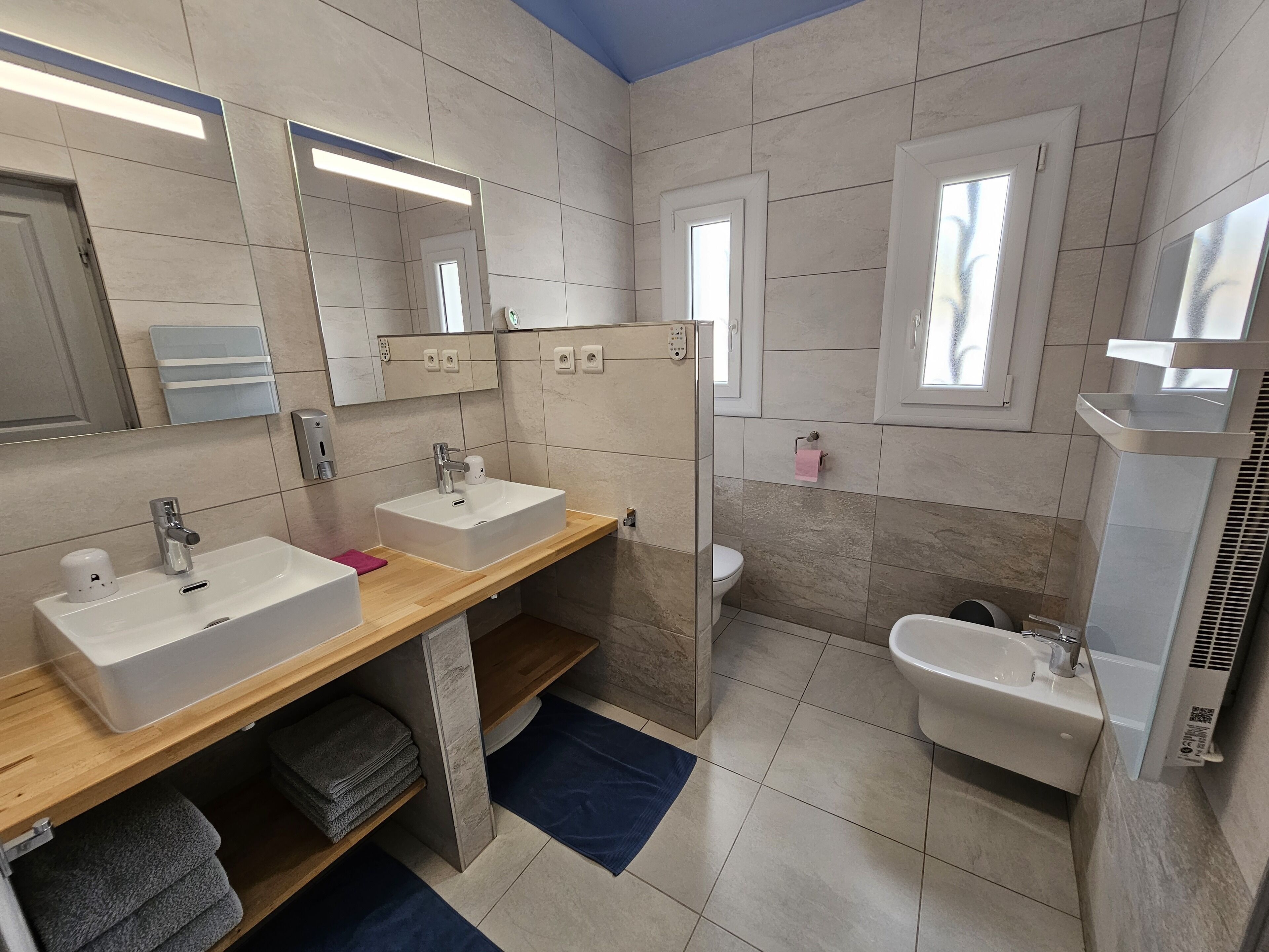 A modern bathroom with two sinks, a toilet, and a shower.