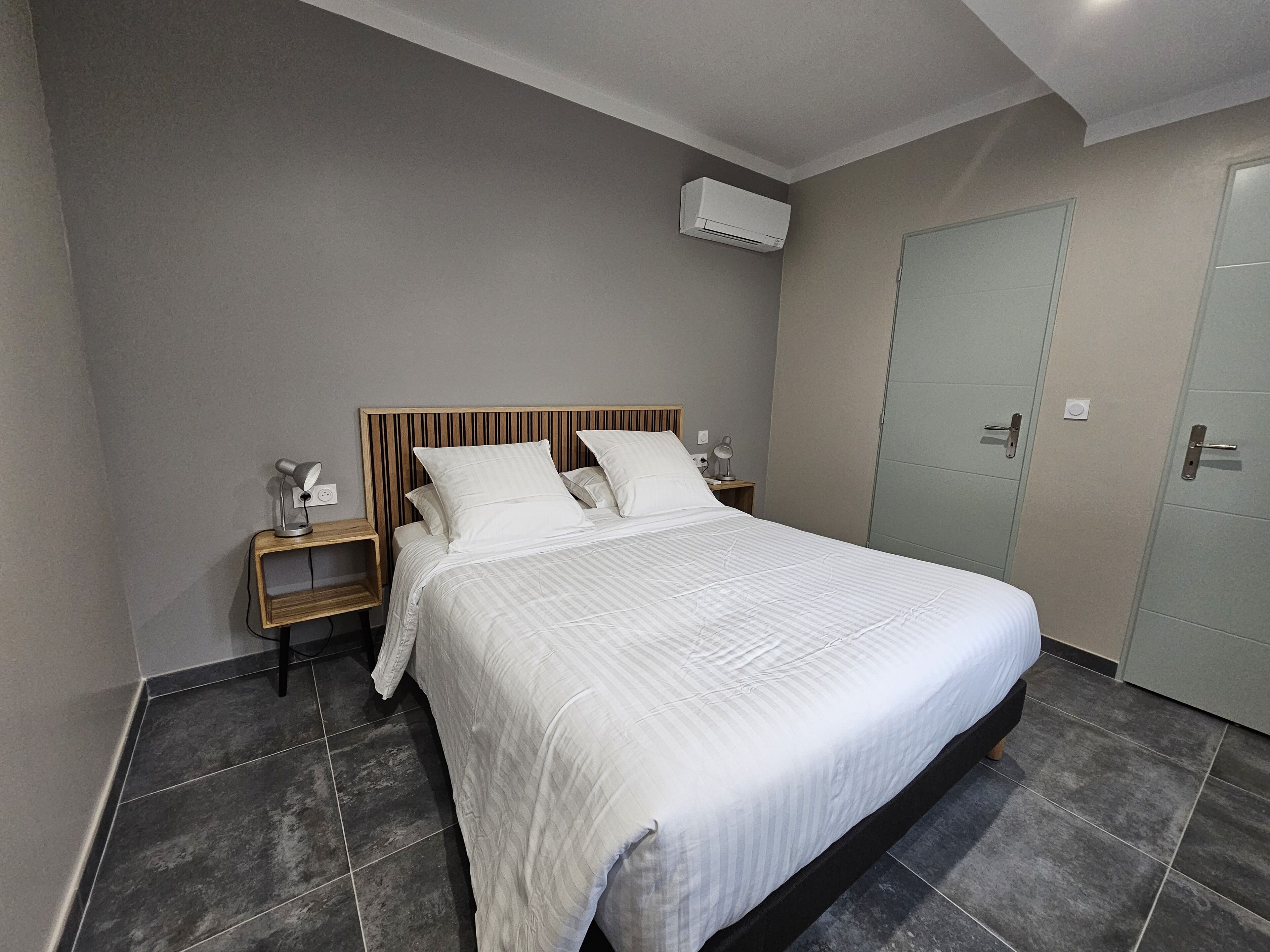 Camera da letto ordinata con un grande letto, un comodino con una lampada, un condizionatore d'aria e un armadio.