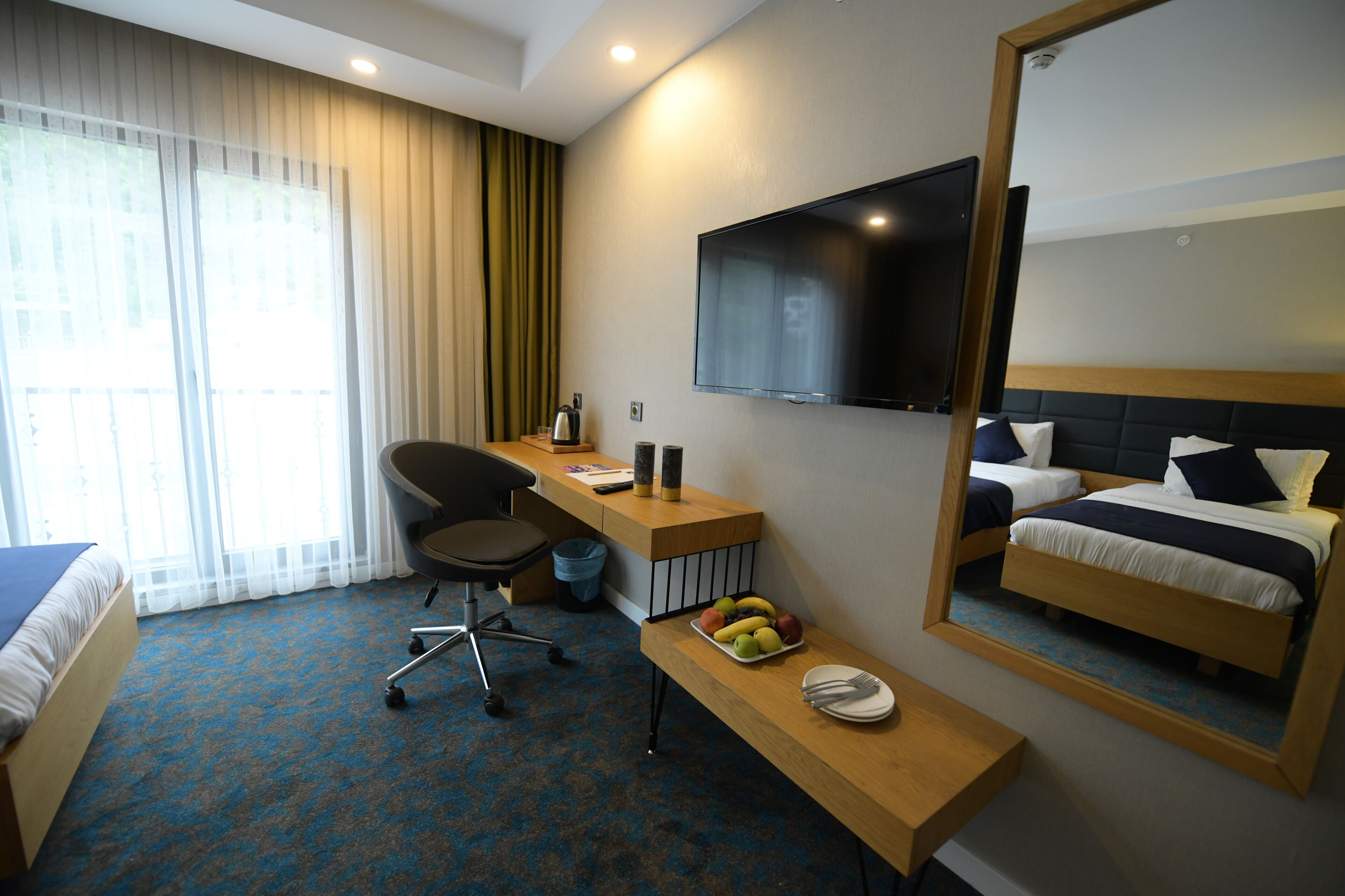 Una habitación de hotel con cama, escritorio, silla y un espejo grande.