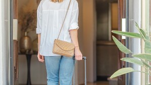 A person exiting a building with a suitcase and a handbag. - Hotel du Golfe (Ajaccio)