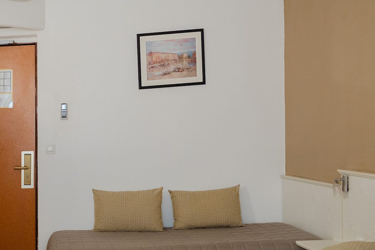 A hotel room with a bed, two pillows, a painting on the wall, and a door.