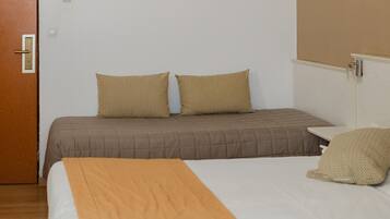 A hotel room with a bed, two pillows, a painting on the wall, and a door.