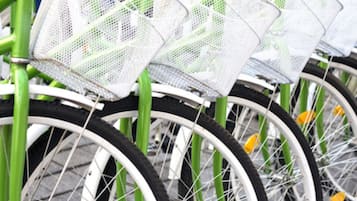 Eine Reihe grüner Fahrräder mit weißen Reifen und Körben vorne.
