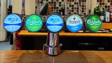Una barra con cuatro grifos de cerveza, cada uno identificado con diferentes marcas y tipos.