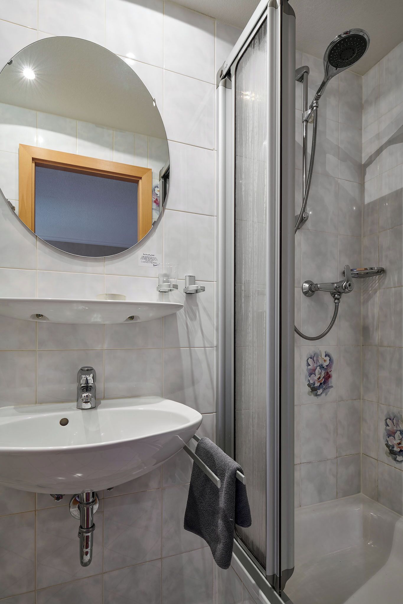 A bathroom with a sink, mirror, and shower.