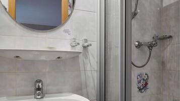 A bathroom with a sink, mirror, and shower.