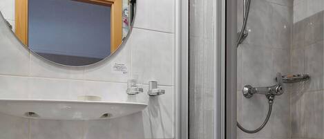 A bathroom with a sink, mirror, and shower.