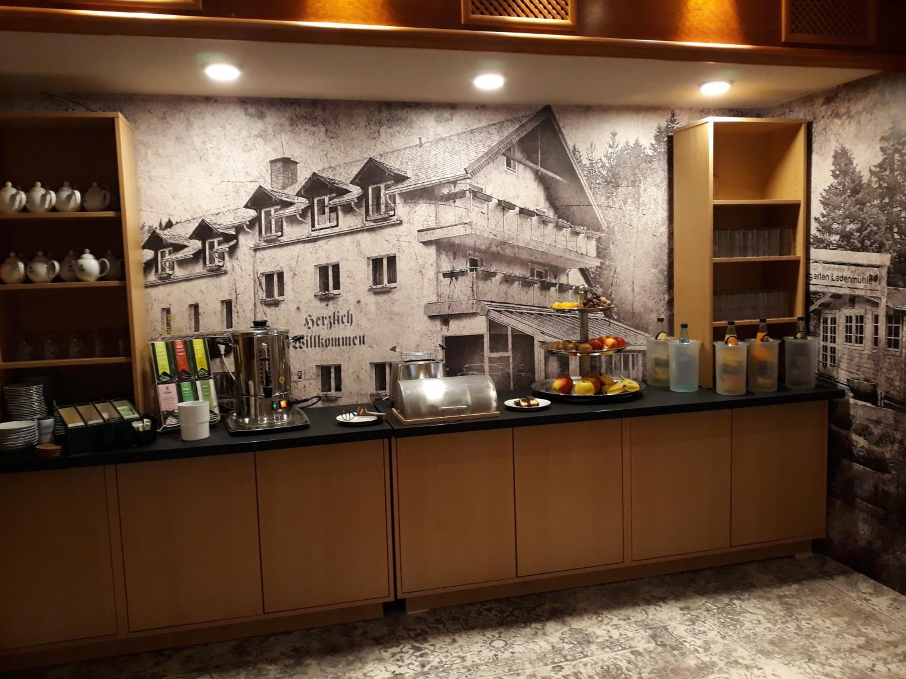 A bar area with a mural of a building, a coffee machine, and various food and drink items.