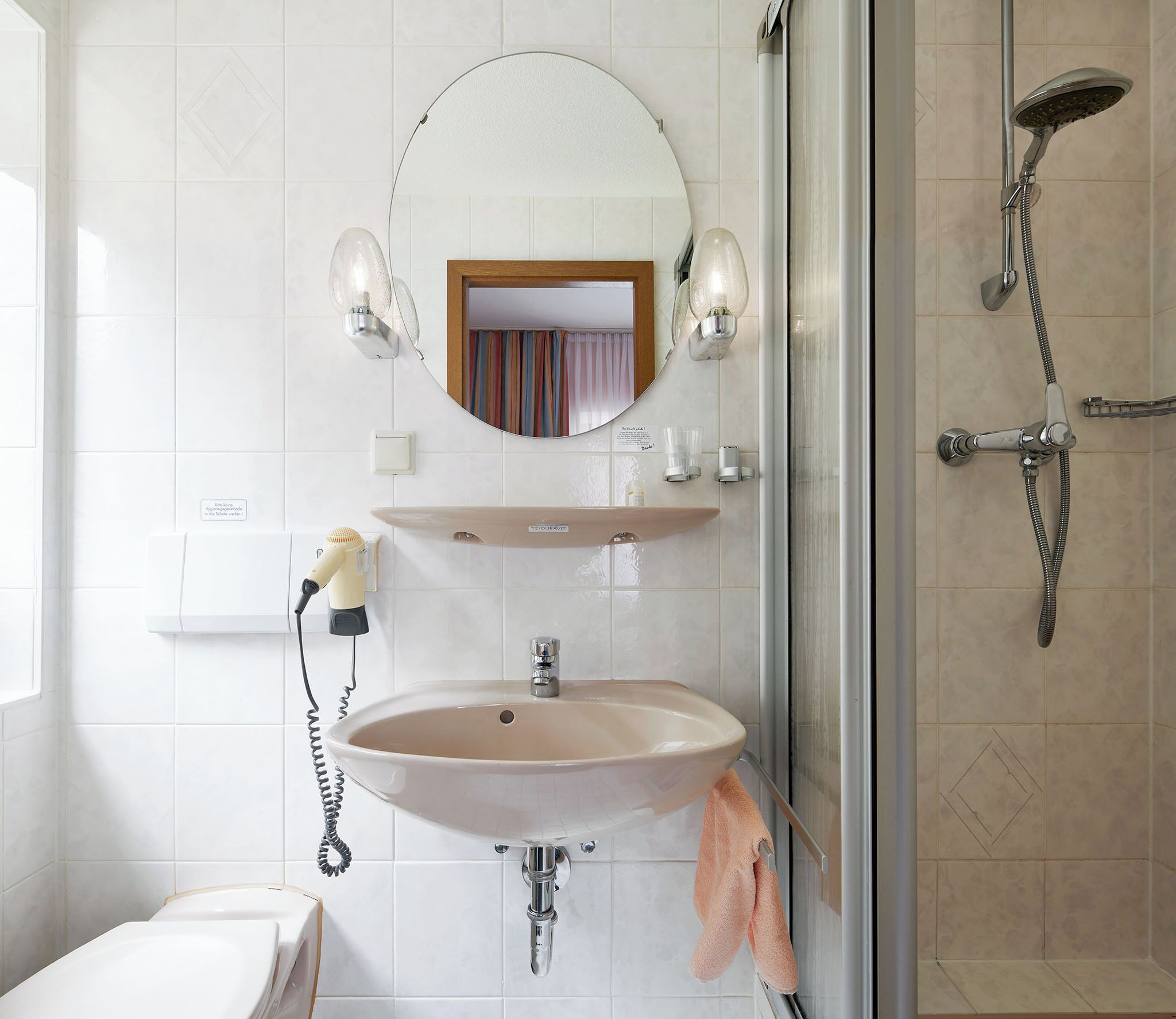 Un baño con lavabo, espejo y ducha.