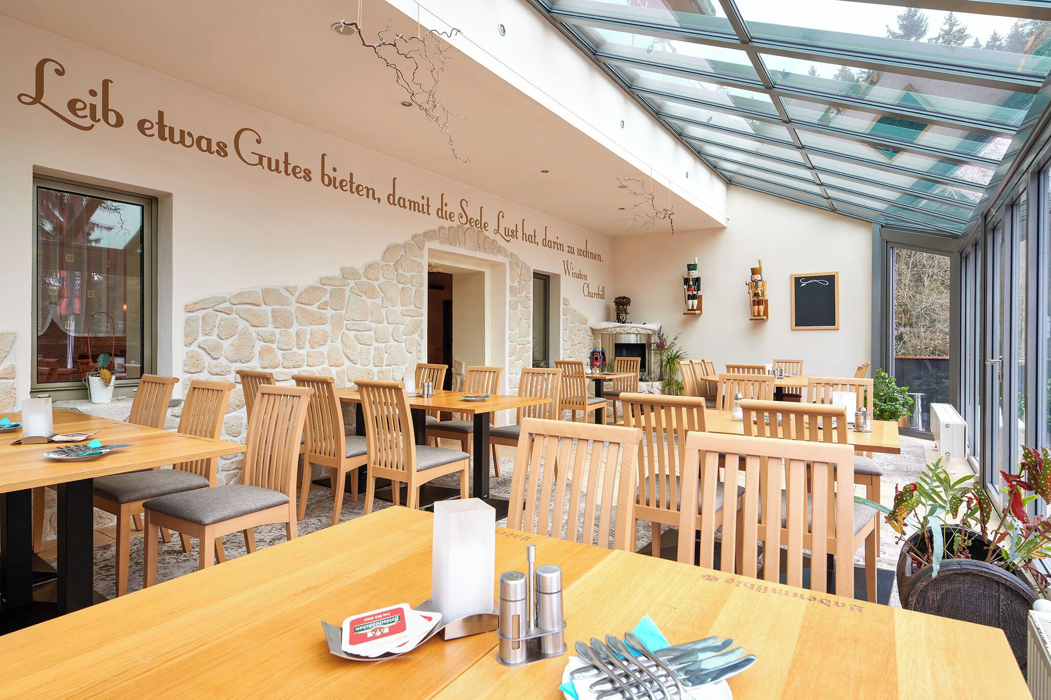 Un restaurant avec des tables et des chaises en bois, des murs en pierre et un plafond en verre.