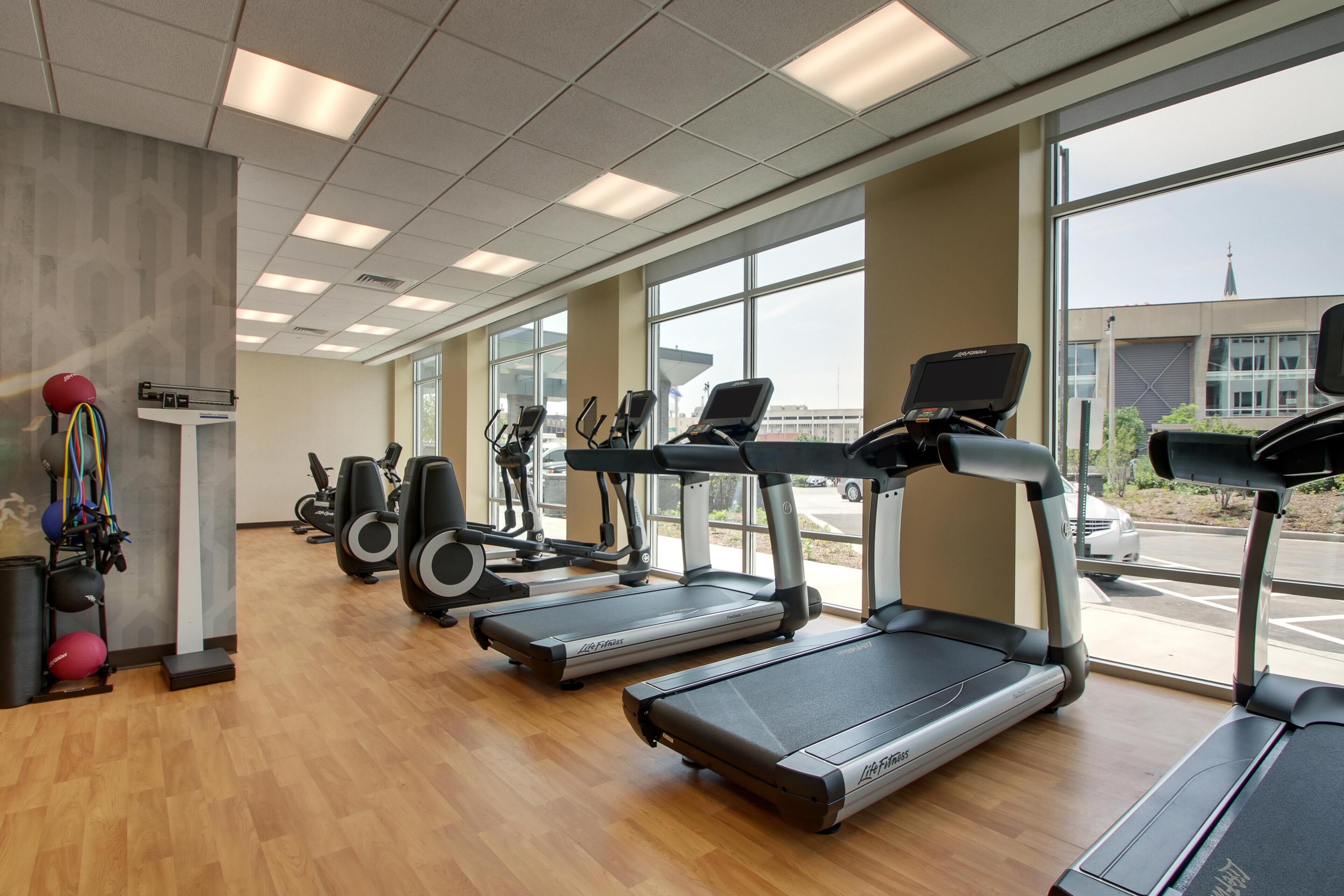 Une salle de sport équipée de tapis de course, de vélos elliptiques et de poids libres.