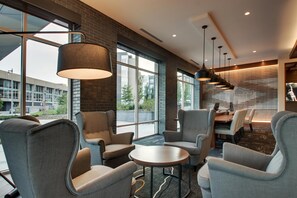 A modern lounge area with large windows, comfortable seating, and a dining area. - Hyatt Place Milwaukee/Downtown (Milwaukee)