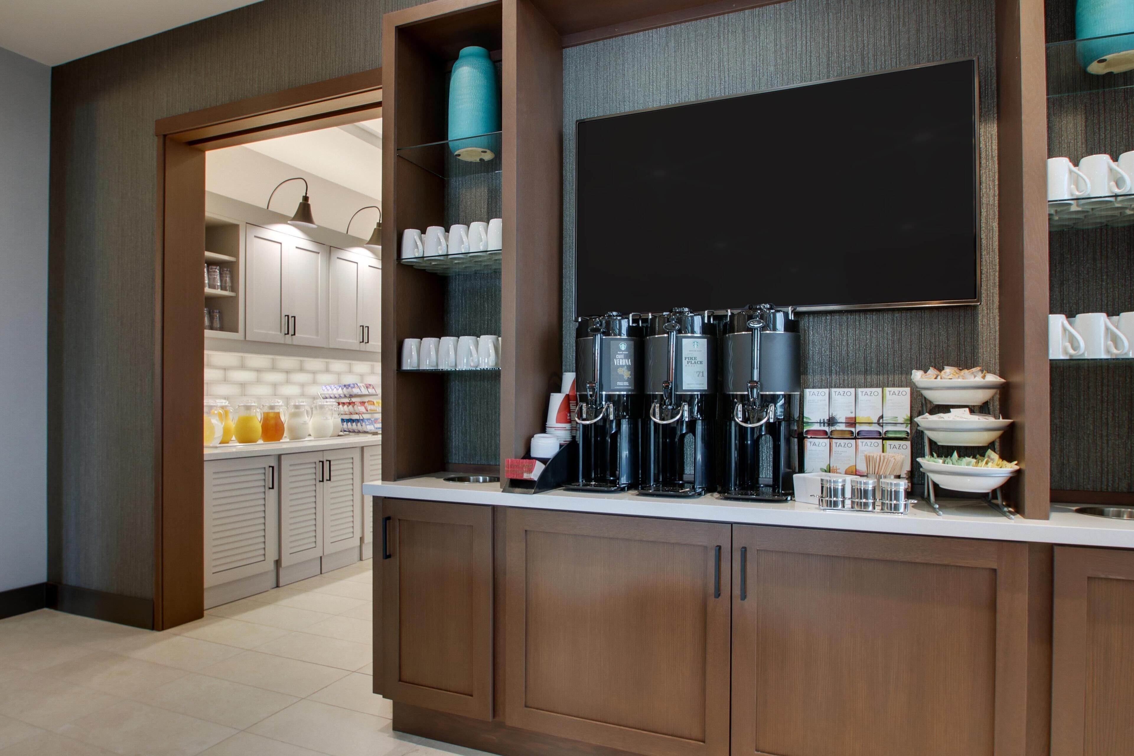 A modern kitchen with a coffee station, breakfast bar, and storage cabinets.