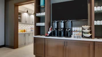 A modern kitchen with a coffee station, breakfast bar, and storage cabinets.
