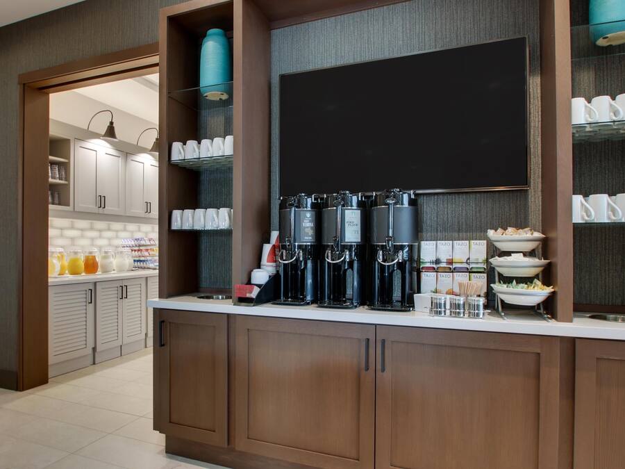 A modern kitchen with a coffee station, breakfast bar, and storage cabinets.