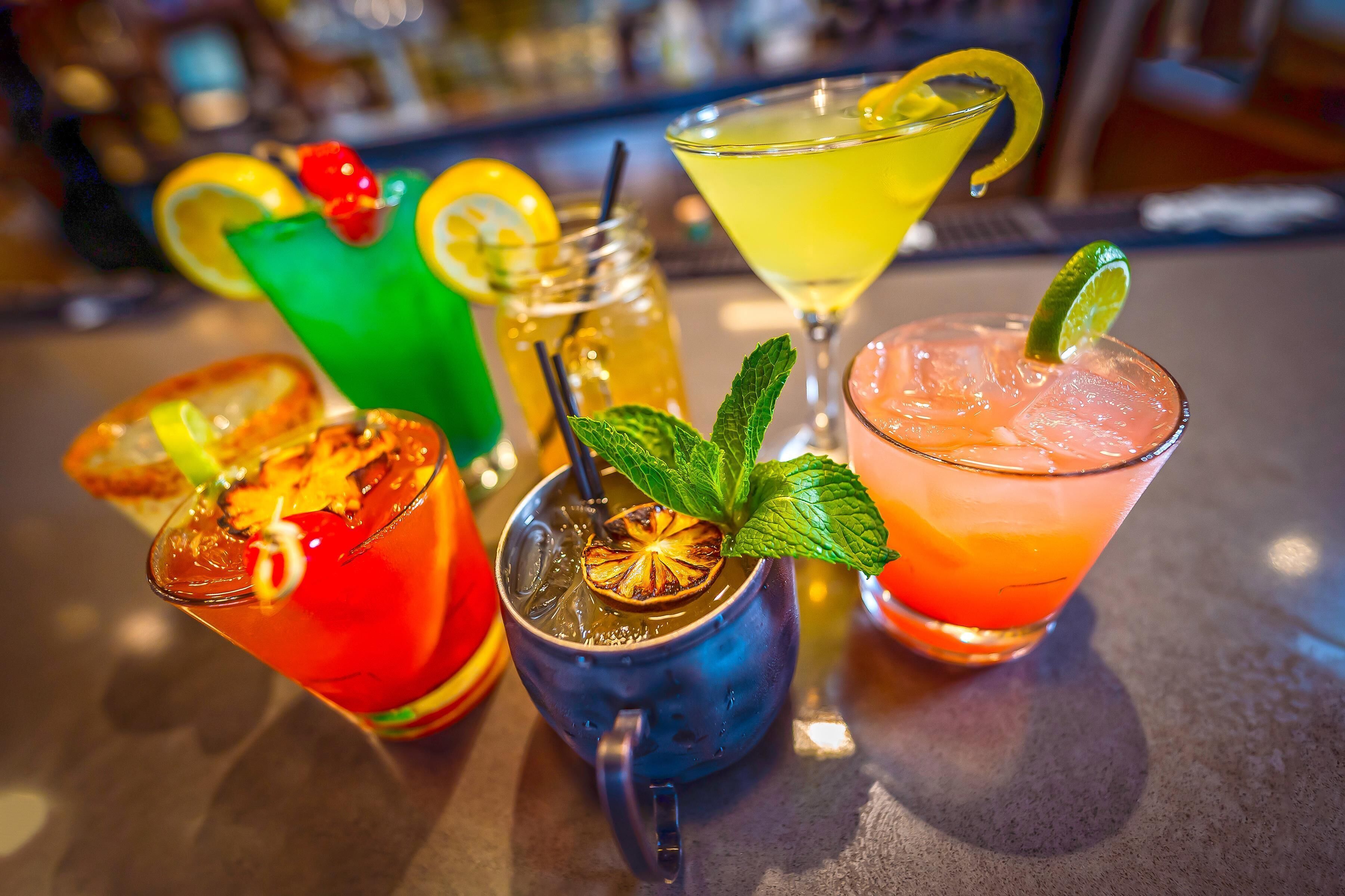 A variety of colorful cocktails on a bar counter.