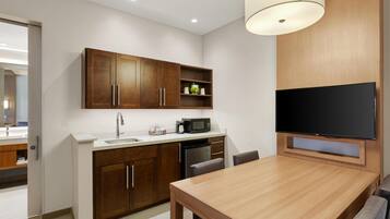 A modern kitchen with wooden cabinets, a built-in microwave, and a flat-screen TV.