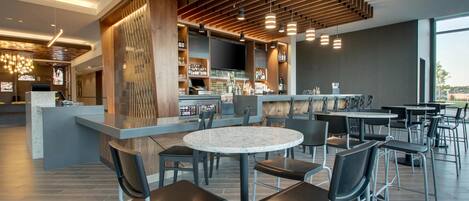 Un área de bar moderna con asientos, una barra y un ventanal grande.