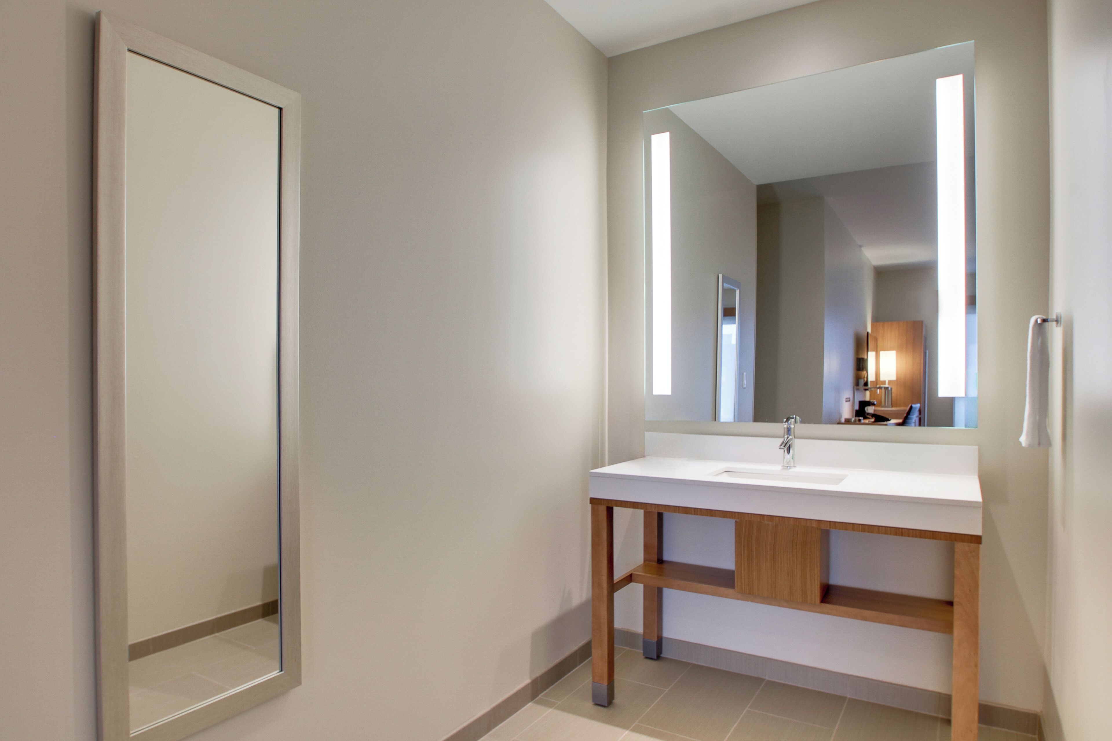 Een moderne badkamer met een witte wastafel, een houten opbergmeubel en een grote spiegel.