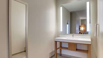 Een moderne badkamer met een witte wastafel, een houten opbergmeubel en een grote spiegel.