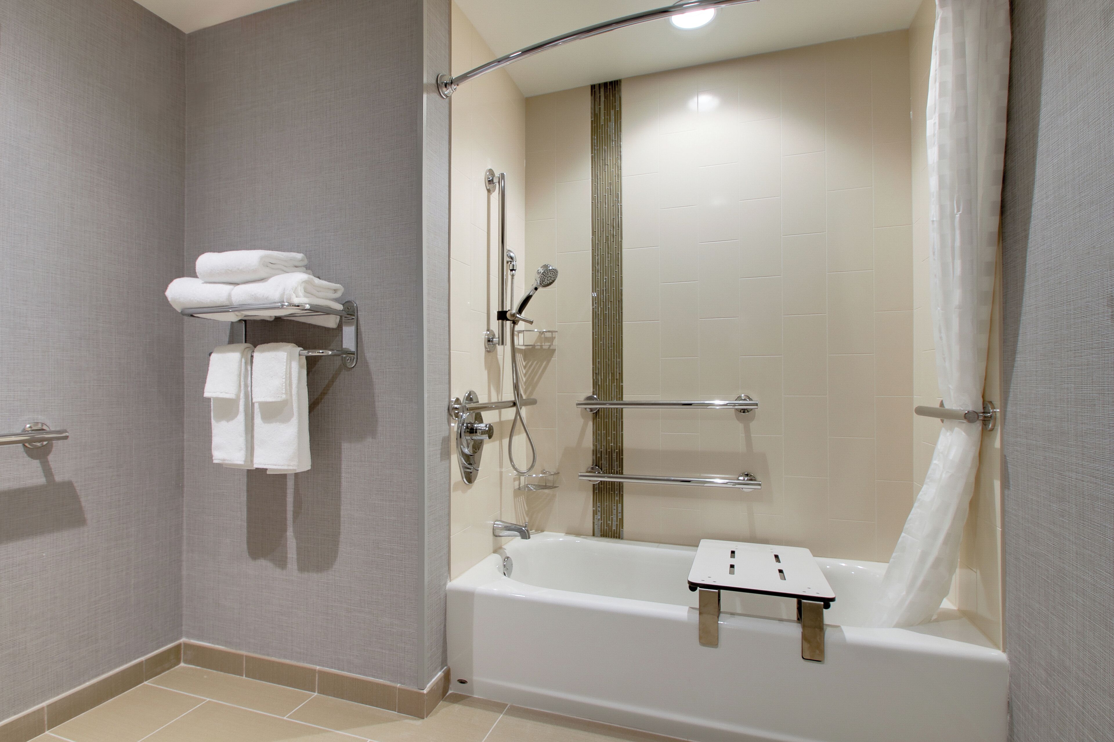 Une salle de bain moderne avec une douche à l’italienne, une baignoire et un porte-serviettes.