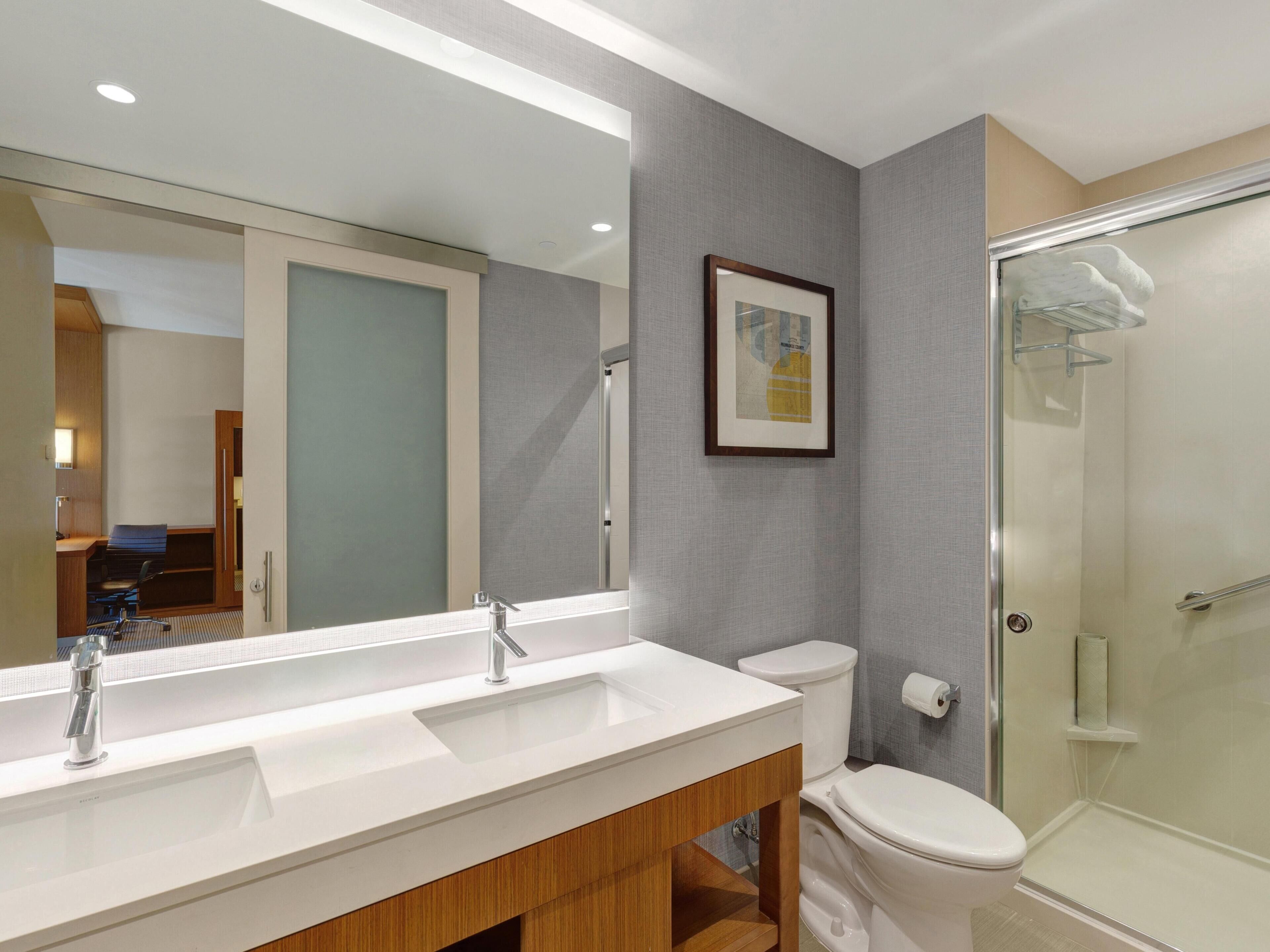 A modern bathroom with a double sink, a toilet, and a glass-enclosed shower.