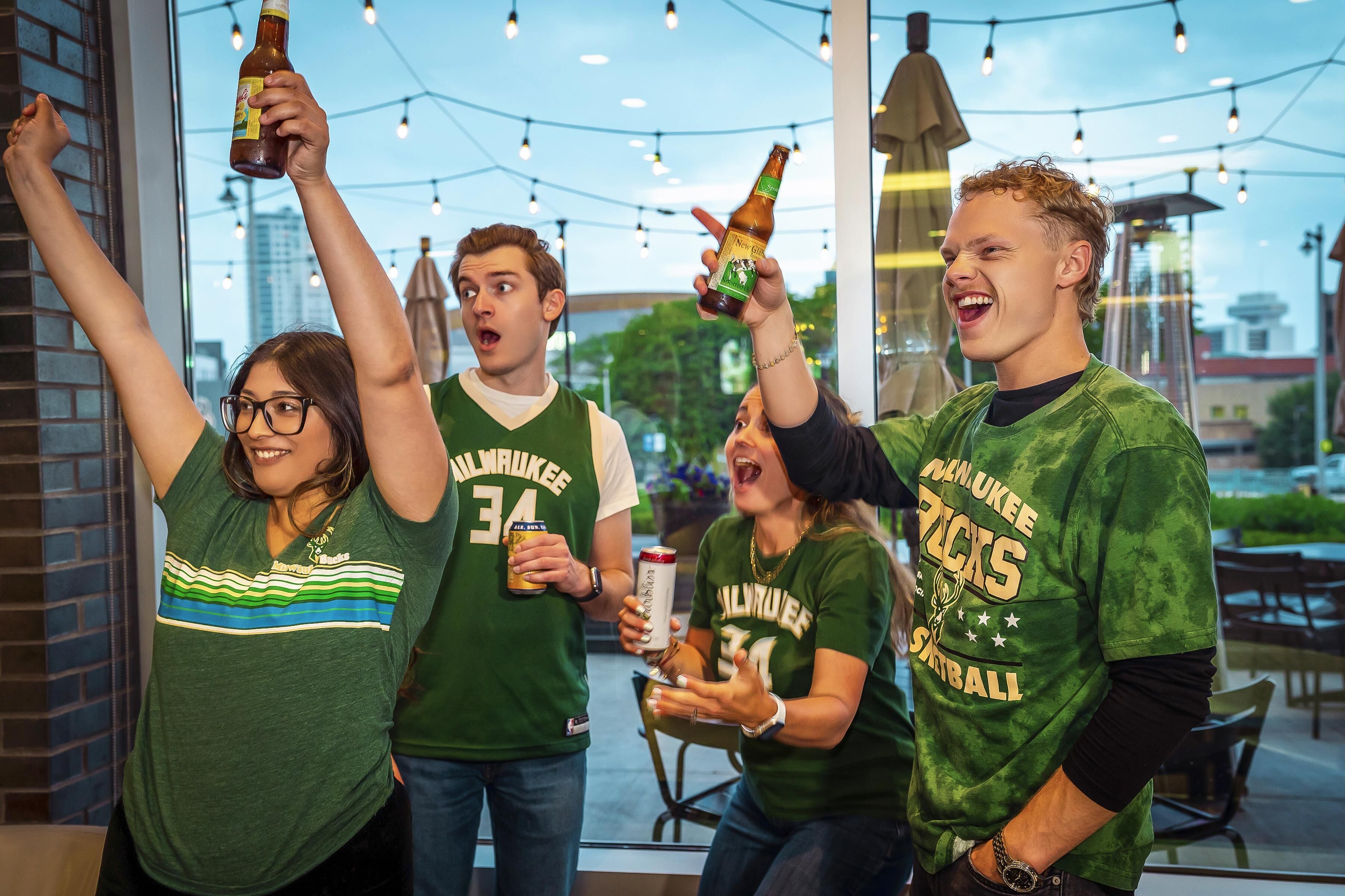 A group of people in a casual outdoor setting, possibly a patio or terrace, with string lights overhead.