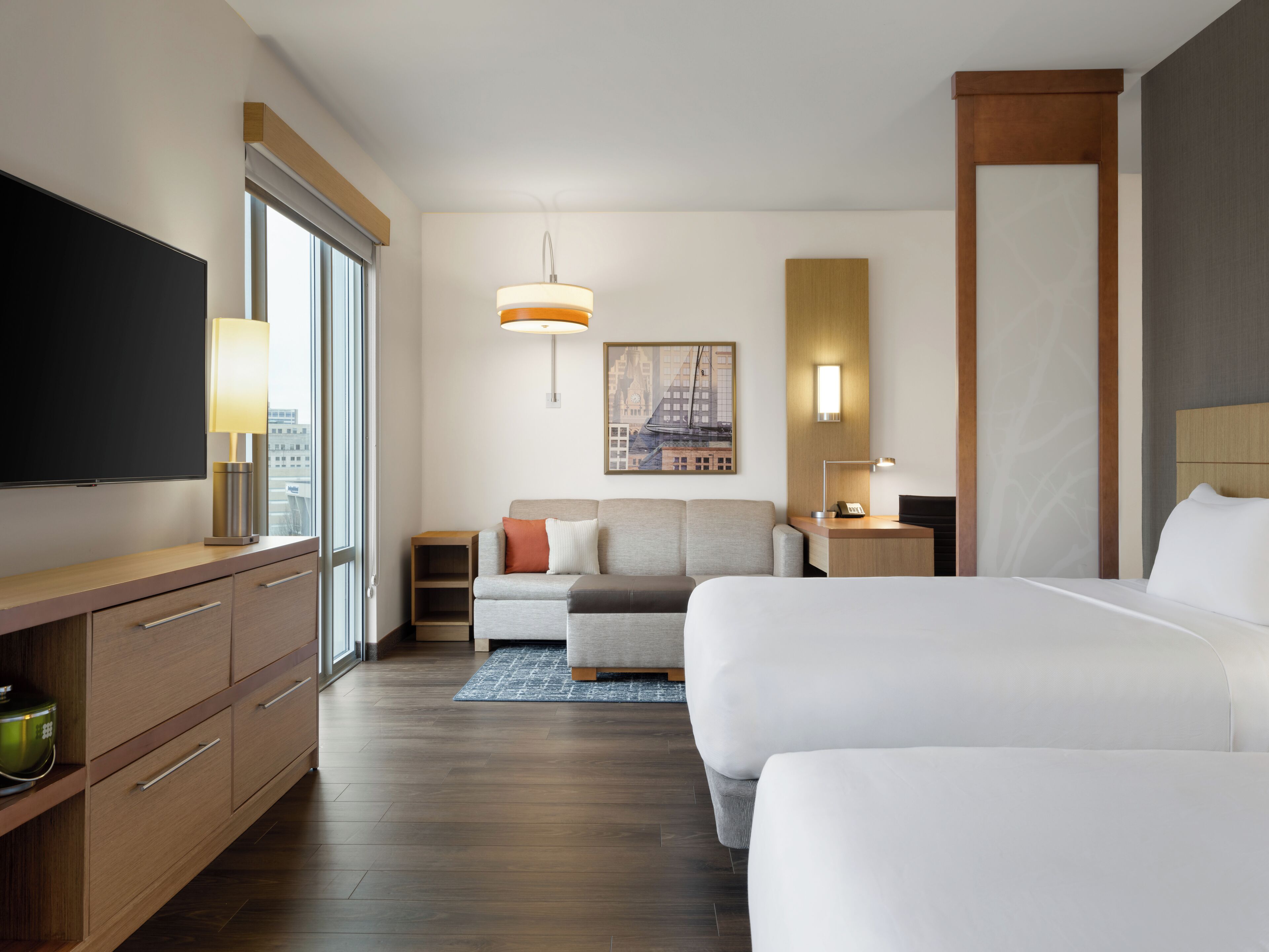 Une chambre d’hôtel équipée d’une télévision, d’un canapé, d’un lit, d’un bureau et d’un tableau au mur.