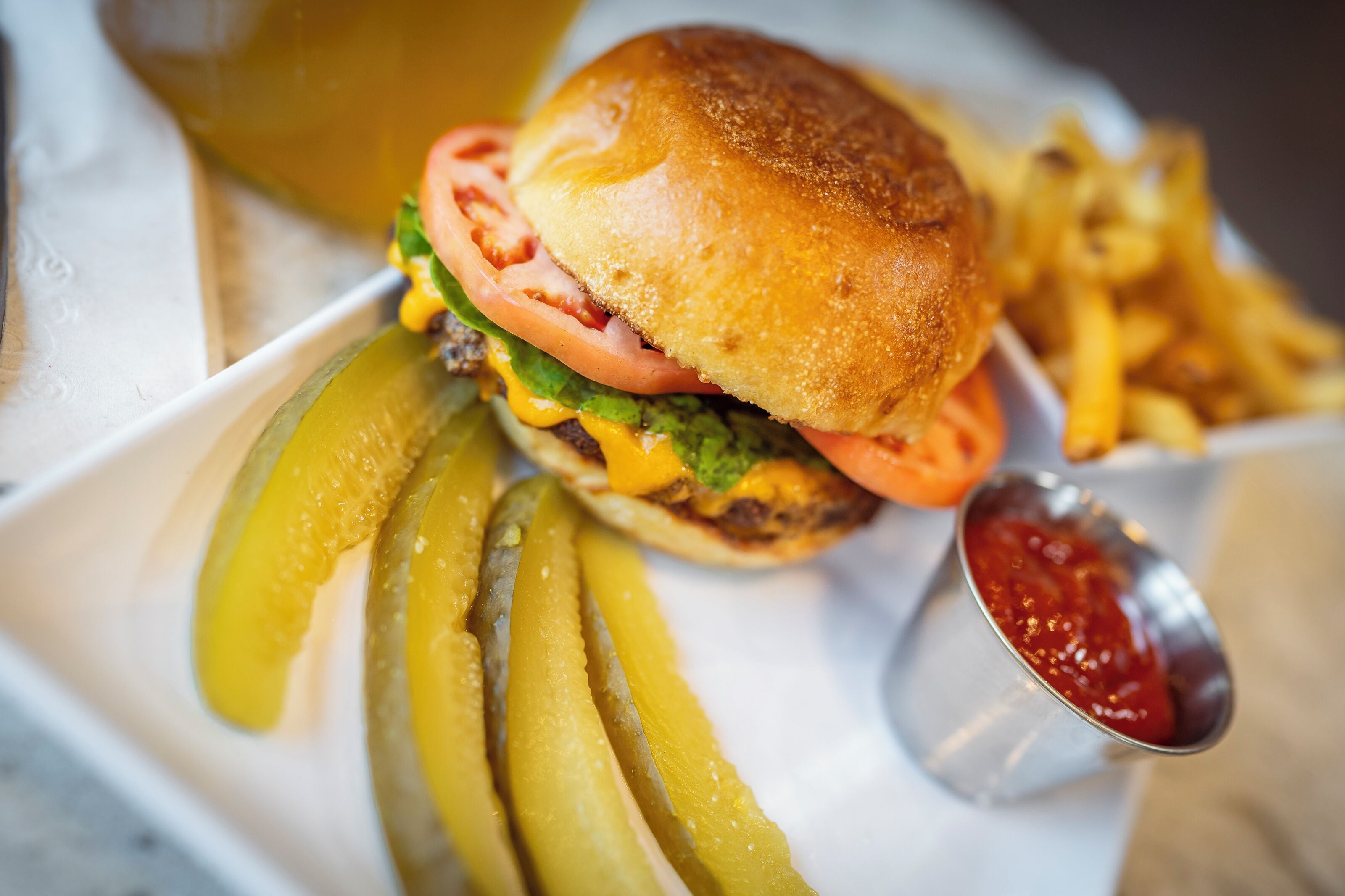 A burger with pickles and fries, served with ketchup.