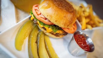 A burger with pickles and fries, served with ketchup.