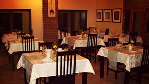 Ein Restaurant mit mehreren Tischen, gedeckt für das Essen, mit weißen Tischdecken und Holzbänken.