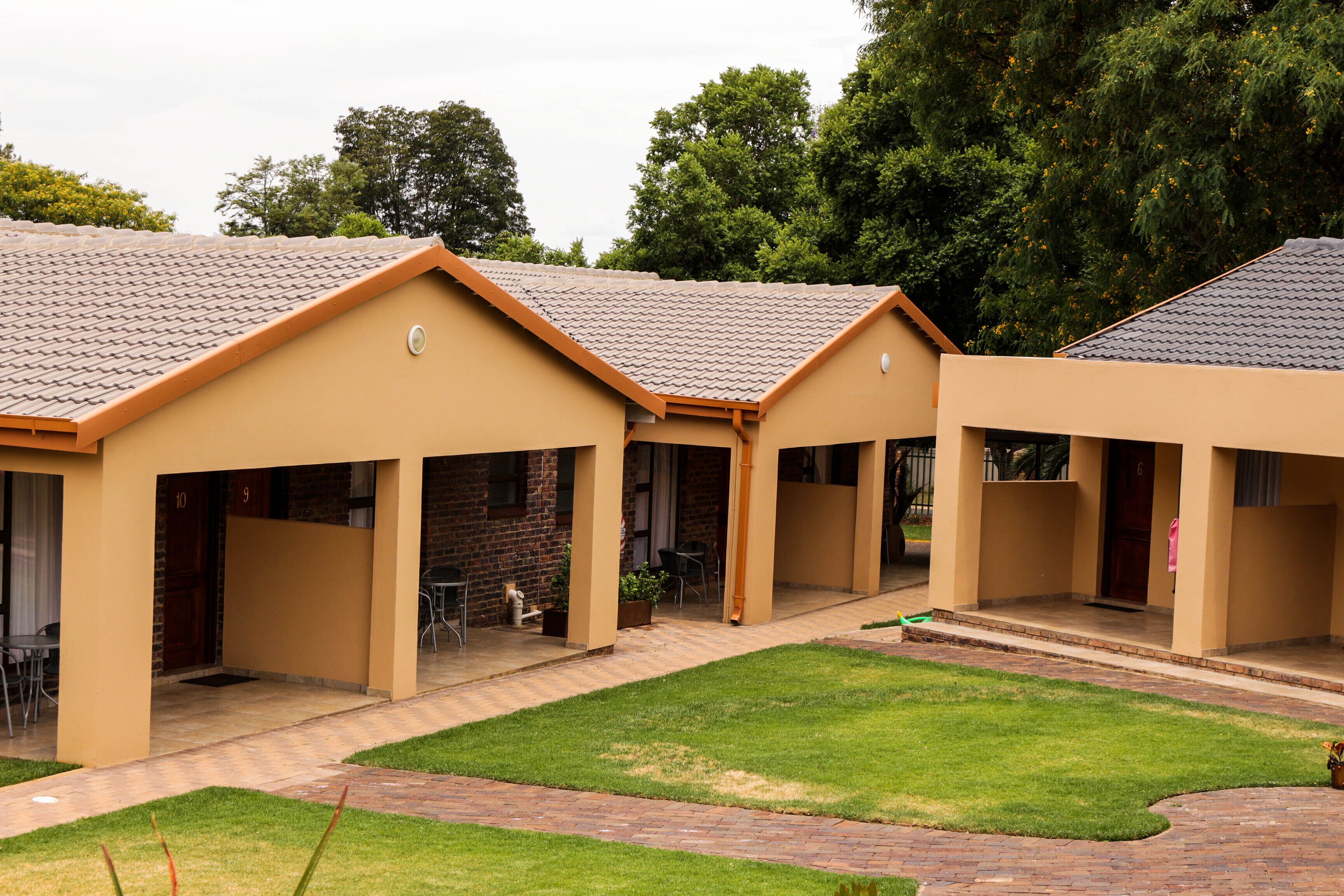 A building with a tiled roof and a brick pathway leading to a covered outdoor seating area.