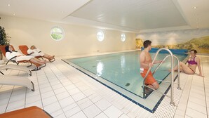 A swimming pool with a tiled floor, lounge chairs, and a mural on the wall. - Hotel Zum Baeren (Altenberg)