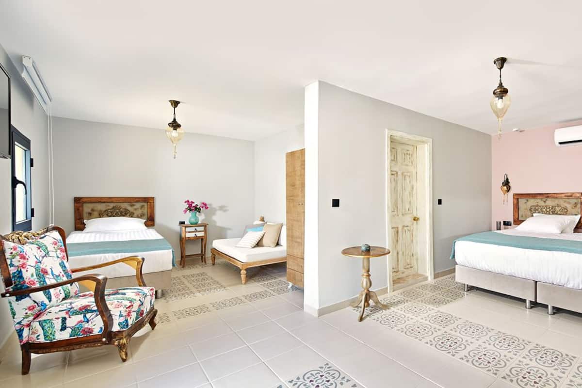 Habitación de hotel con dos camas, zona de estar con una silla, una mesita y un escritorio con un espejo y una bandeja.