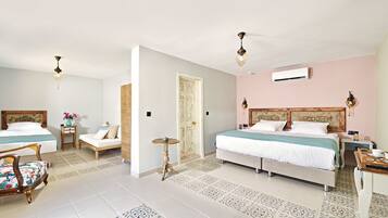 Habitación de hotel con dos camas, zona de estar con una silla, una mesita y un escritorio con un espejo y una bandeja.
