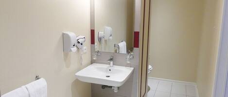 A bathroom with a sink, mirror, towel rack, and a shower area.