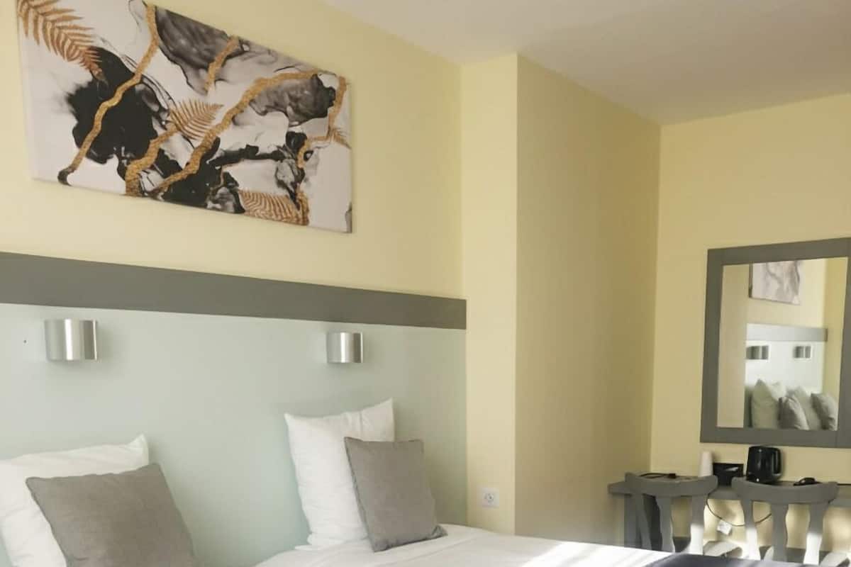 Une chambre d’hôtel avec un lit, deux tables de chevet, un miroir et un tableau au mur.