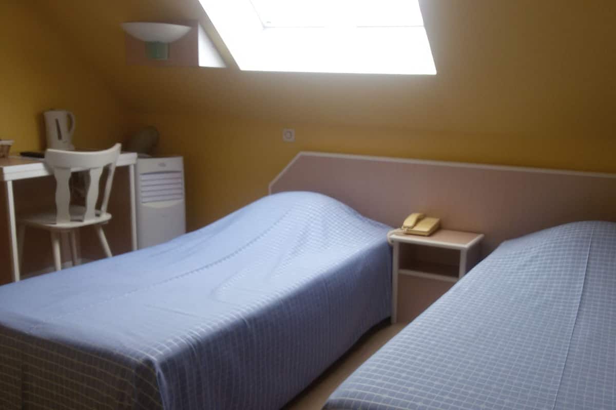 Une chambre avec deux lits, un bureau, une chaise et un téléphone.